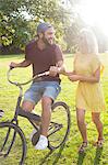 Young couple cycling in sunlit park