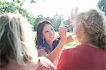 Female adult friends applying make up at sunset park party