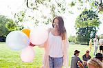 Young woman with bunch of balloons at park party