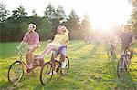 Crowd of partygoing adults arriving on bicycles to sunset park party