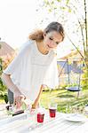 Teenage girl pouring fruit juice at patio table