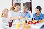 Teenage girl lighting birthday cake candles for children at patio table