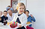 Female toddler carrying birthday cake on patio