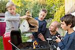 Mid adult man and sons preparing barbecue in garden