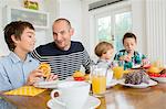 Mid adult man and family having tea at kitchen table