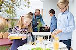 Girl and brother pouring juice at garden barbecue table