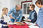 Father serving food to children at garden barbecue table