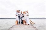 Group of friends standing on pier, holding wine glasses