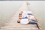 Group of friends lying in a row, on pier