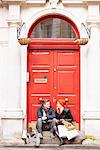 Young shopping couple taking a break on doorstep, London, UK