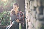 Mid adult woman using digital tablet in gardens at Thornbury Castle, South Gloucestershire, UK