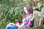 Mid adult woman reading on garden bench at Thornbury Castle, South Gloucestershire, UK