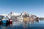 Fishing boats in harbour and snow capped mountains, Svolvaer, Lofoten Islands, Norway