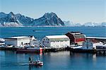 Fishing boat sailing by industrial buildings, Svolvaer, Lofoten Islands, Norway