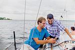 Men on sailboat looking at mobile phone smiling