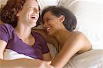 High angle view of lesbian couple lying in bed hugging, laughing