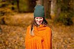 Young woman wrapped in orange blanket in autumn forest