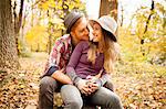 Romantic young couple sitting in autumn forest