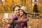 Young couple taking smartphone selfie in autumn forest