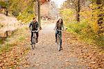 Happy young couple cycling on riverside in autumn