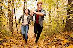 Romantic young couple running through autumn forest