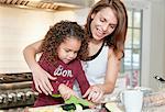 Mother helping daughter chop vegetables in kitchen