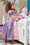 Side view of girl dressed up as princess play acting with teddy bear