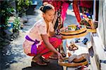 Woman placing religious offering on doorstep at a Balinese wedding, Petulu Village near Ubud, Bali, Indonesia