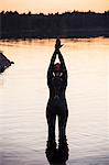 Swimmer standing in water at sunset