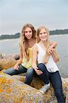 Sisters sitting on rocks at sea
