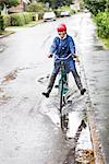 Woman riding bicycle through puddle