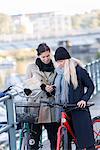 Women with bicycles looking at map in cell phone