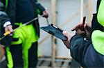 Mid-section of construction worker opening note pad