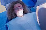 Little girl sitting in dentists chair wearing protective glasses