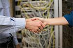 Technicians shaking hands in server room