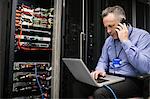 Technician using laptop in server room
