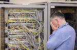 Stressed technician looking at open server locker