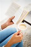 Close up view of woman holding cup of coffee and book