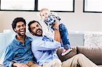 Happy gay couple playing with child