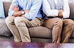 Gay couple sitting back-to-back after arguing