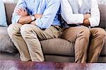 Gay couple sitting back-to-back after arguing