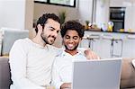 Happy gay couple using laptop