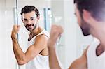 Smiling man looking at his biceps in mirror