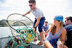 Adult friends preparing crab trap on fishing boat, Nehalem Bay, Oregon, USA