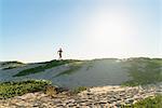 Young man running along sand dunes