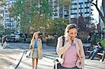 Young woman talking on smartphone whilst walking through city park