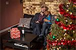 Male couple sitting on sofa, relaxing, at Christmas