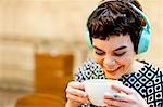 Mid adult woman, wearing headphones, holding coffee cup, smiling