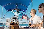 Man behind wheel of sailboat, enjoying view with friends