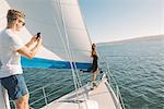 Couple taking photograph on sailboat, San Diego Bay, California, USA